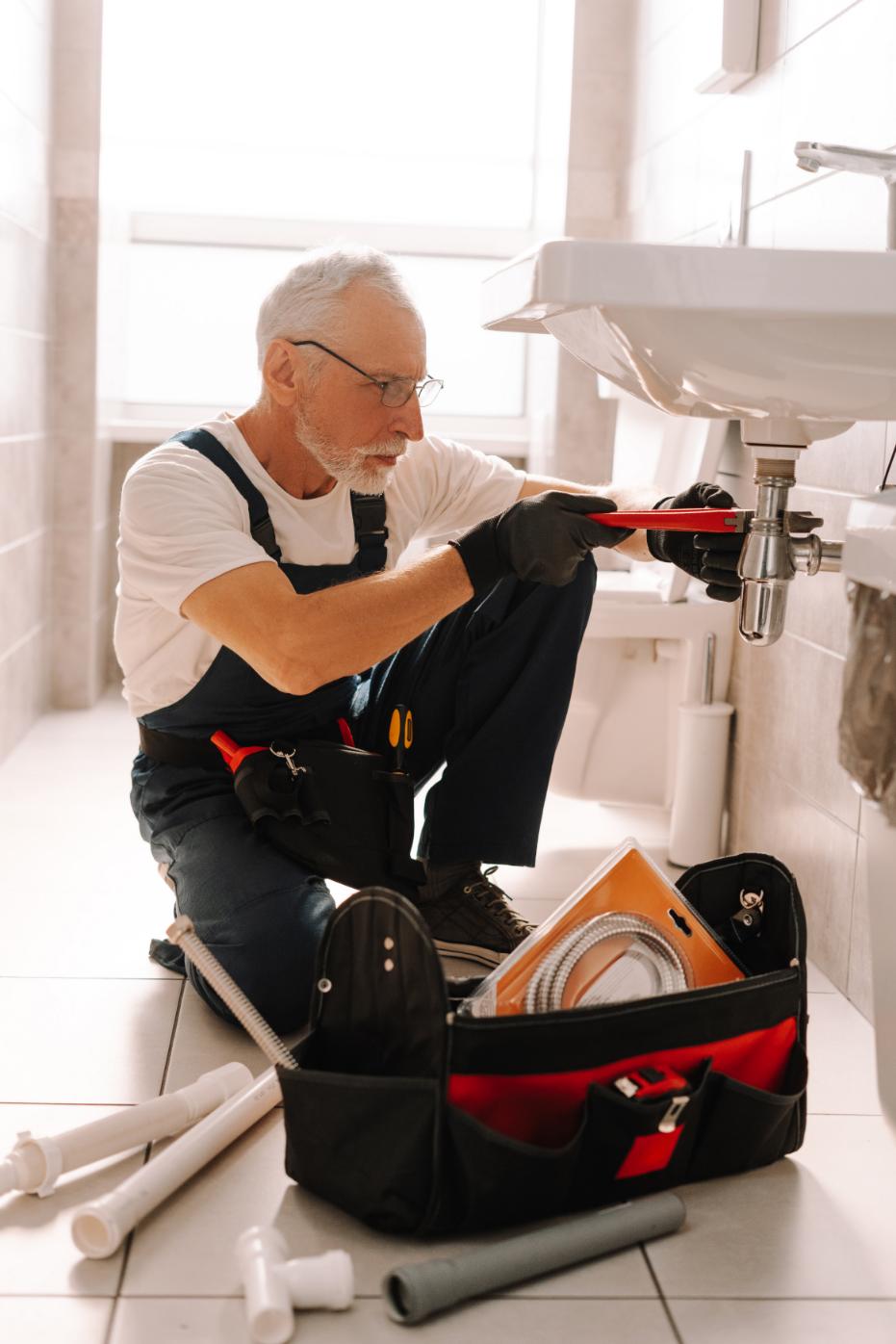 Plumber installing a sink trap with an adjustable wrench
